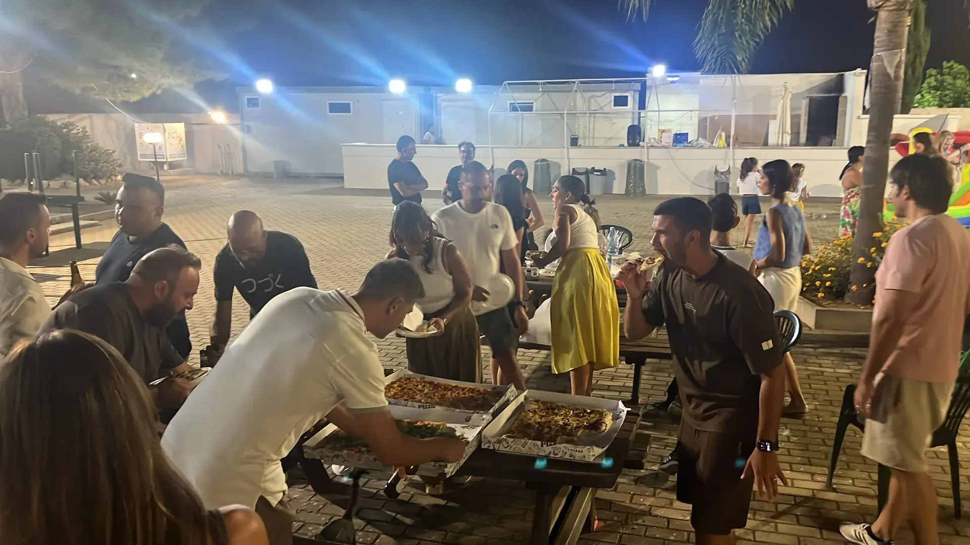 Ospiti adulti che si servono pizza durante una festa serale al Champions Park